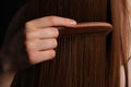 Long brown tape-in hair extensions being combed