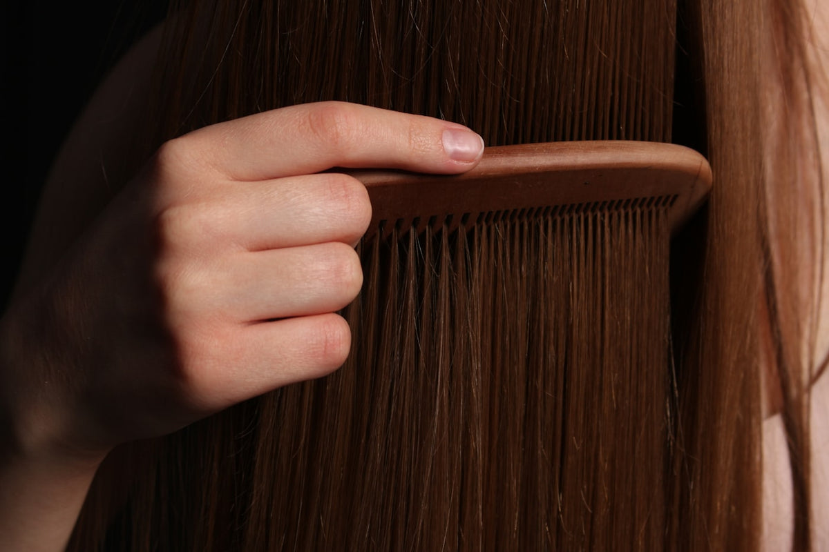 Long brown tape-in hair extensions being combed